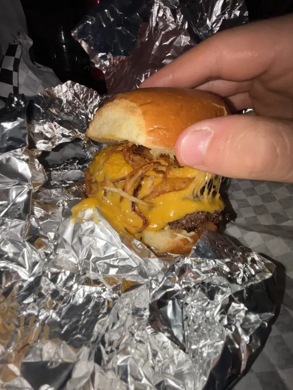 Smash burger con cheddar fuso e cipolla croccante, ancora nella carta stagnola