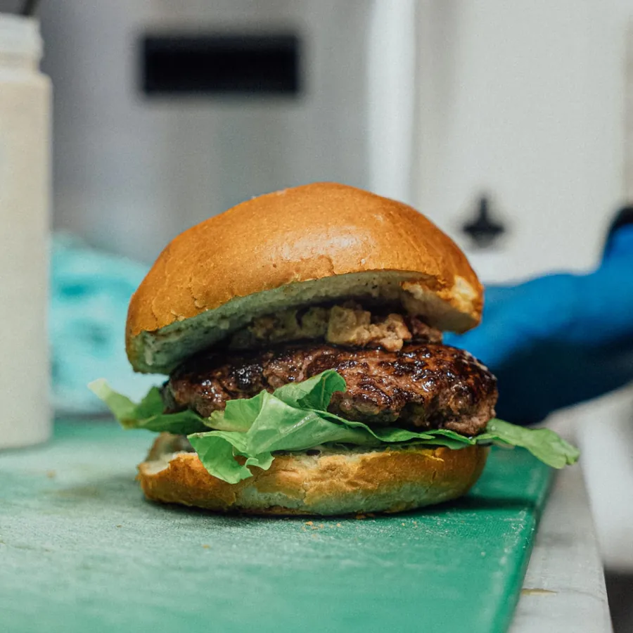 Burger con lattuga appena composto sul tagliere verde del banco